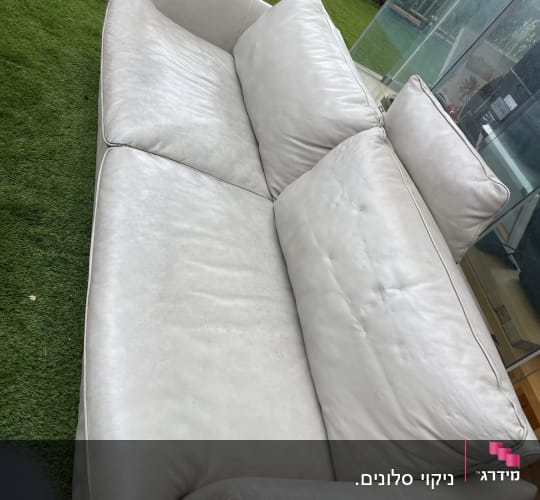 ספה לבנה על דשא מלאכותי בחדר שמש